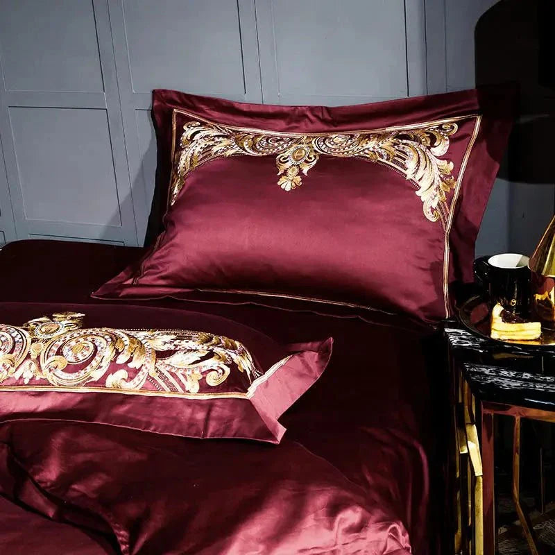 Elegant red Egyptian Cotton Sheets with embroidered pillows and matching decorative accessories.